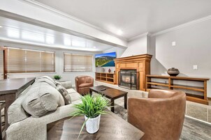 Una sala de estar moderna con chimenea, muebles de cuero y un ventanal con persianas.