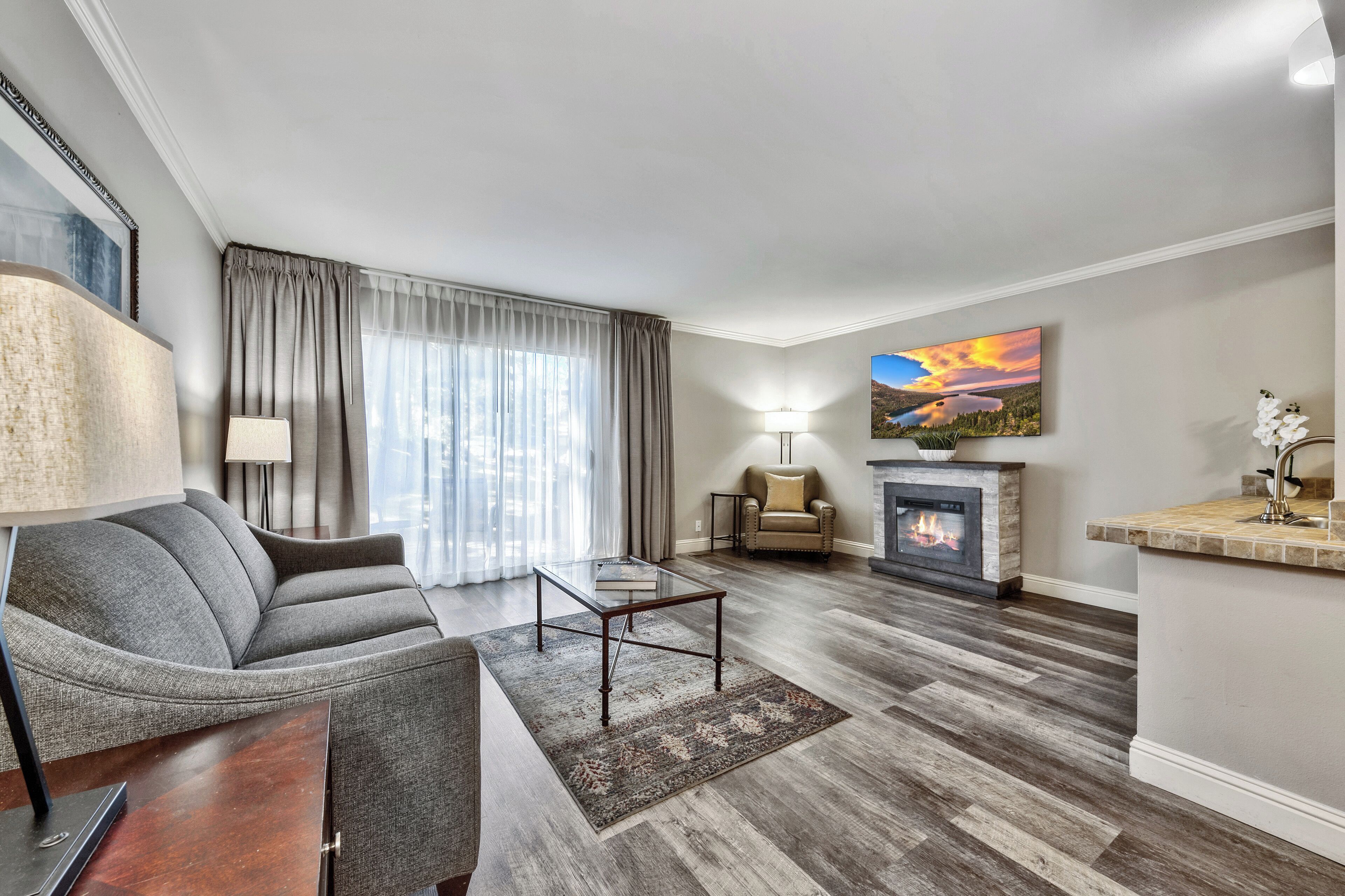 A modern living room with a sofa, coffee table, fireplace, and a painting on the wall.