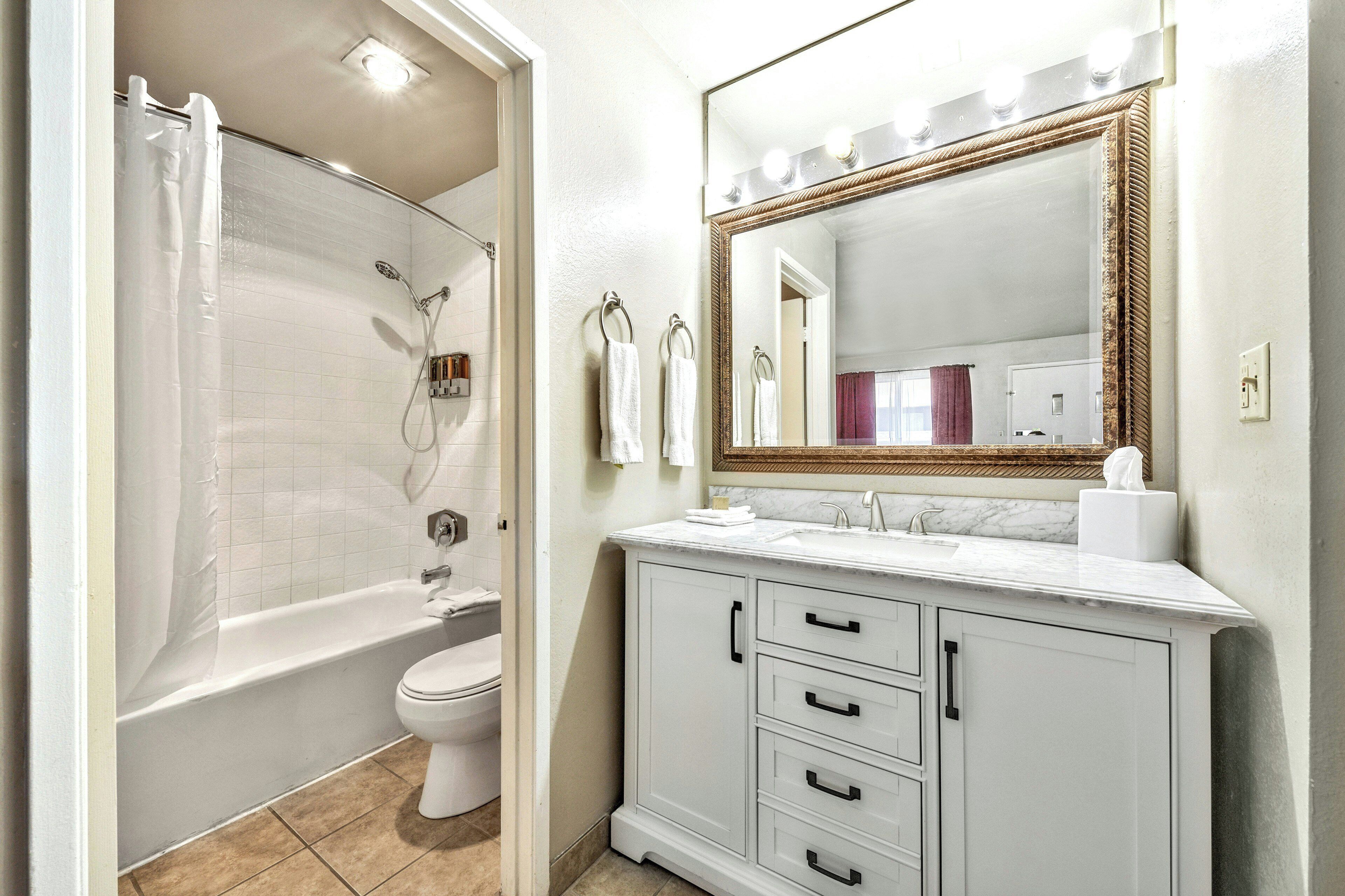 Een badkamer met douche, toilet, wastafel met lades en een grote spiegel.
