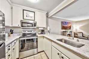 Una cocina moderna con electrodomésticos de acero inoxidable, horno empotrado y una isla grande con lavamanos.