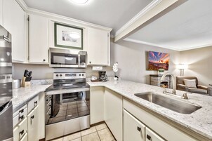 Una cocina moderna con electrodomésticos de acero inoxidable, horno empotrado y una isla grande con lavamanos.