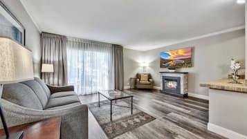 A modern living room with a sofa, coffee table, fireplace, and a painting on the wall.