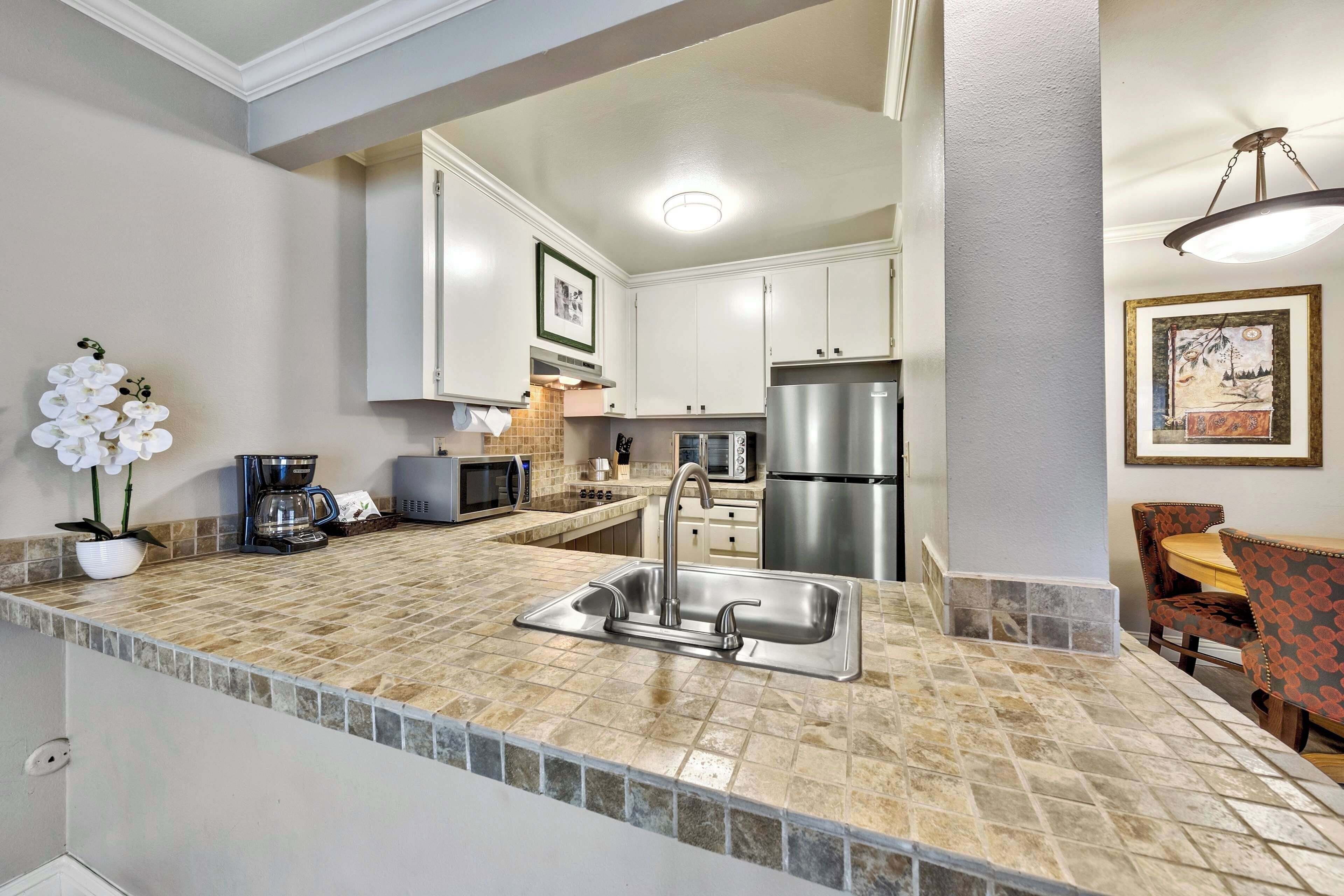 A kitchen with a stainless steel sink, a microwave, a toaster, and a refrigerator.