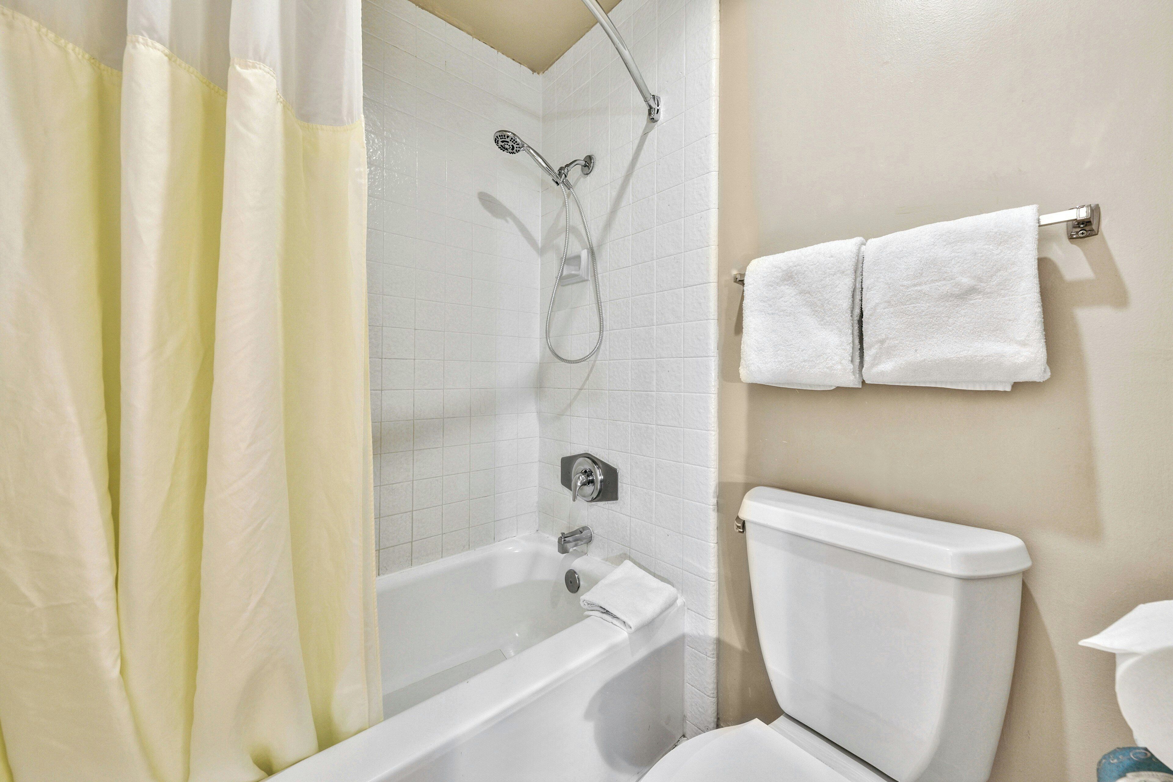 A bathroom with a bathtub, shower, and toilet.