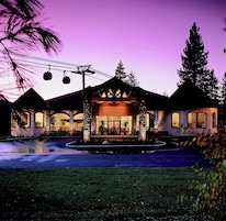 A hotel with a central entrance, multiple windows, and a landscaped front yard.