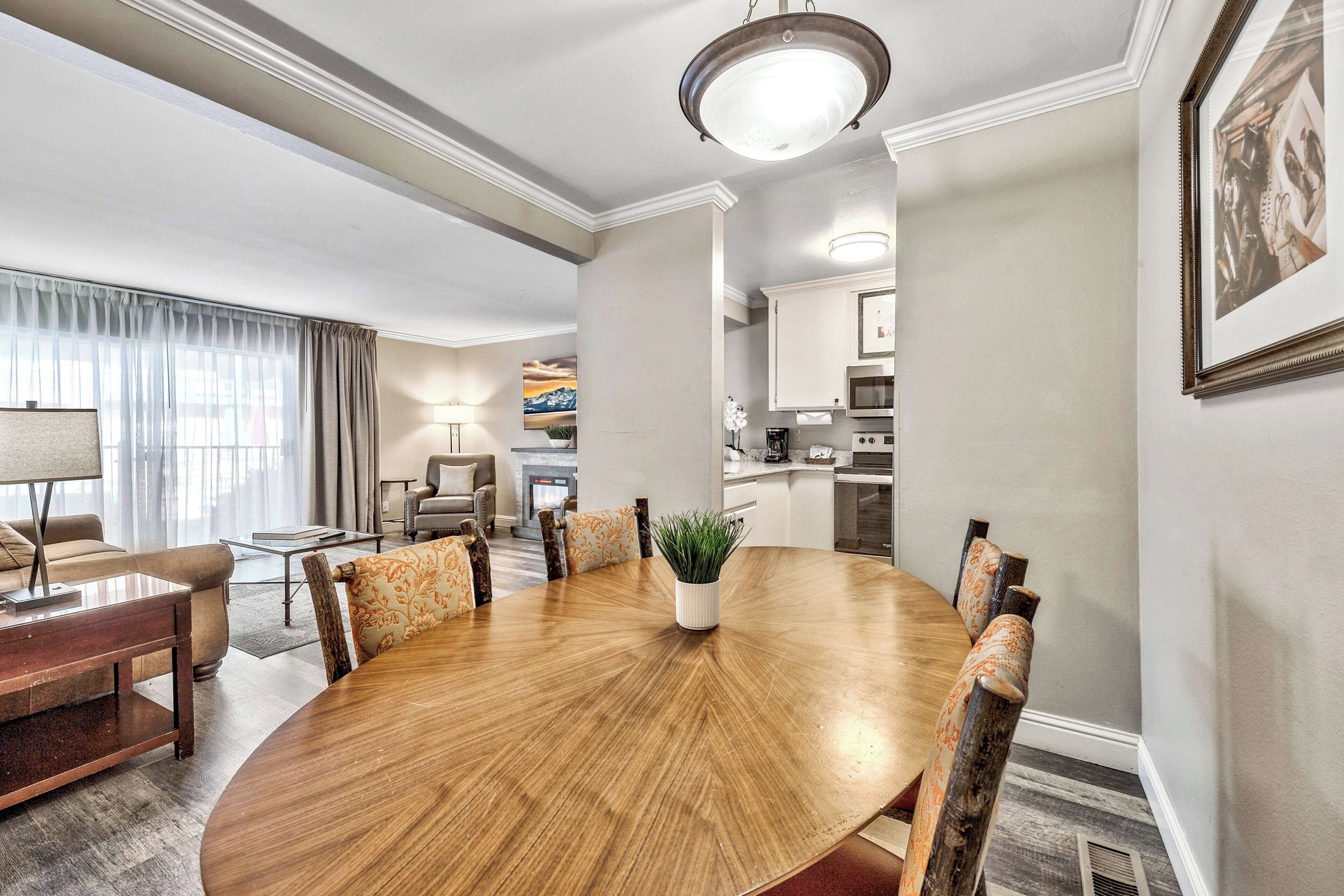 Un comedor de hotel con una mesa redonda de madera, sillas, una planta en maceta y un cuadro en la pared.