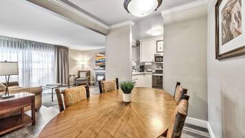 Un comedor de hotel con una mesa redonda de madera, sillas, una planta en maceta y un cuadro en la pared.