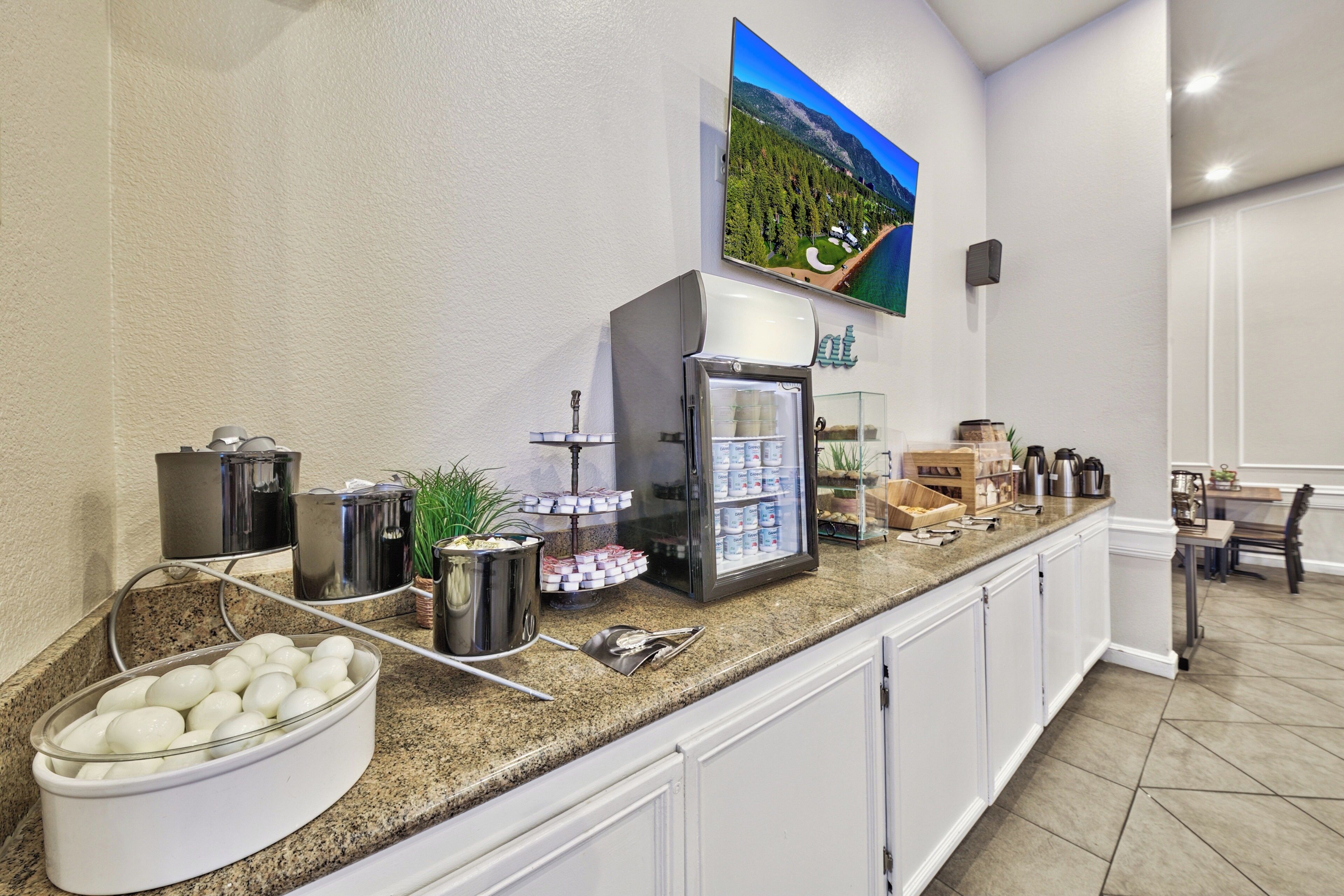 A kitchen area with a granite countertop, a coffee machine, a refrigerator, and a bowl of eggs.