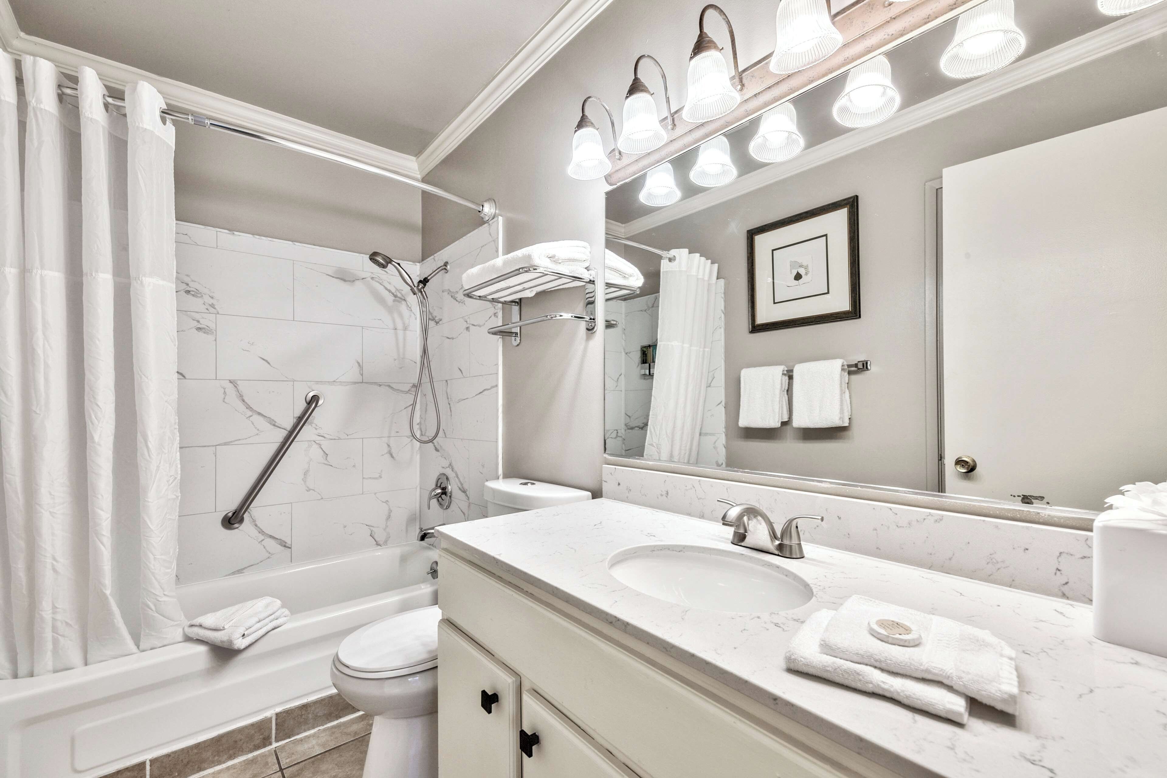 A modern bathroom with a walk-in shower, a vanity with a sink, and a large mirror.