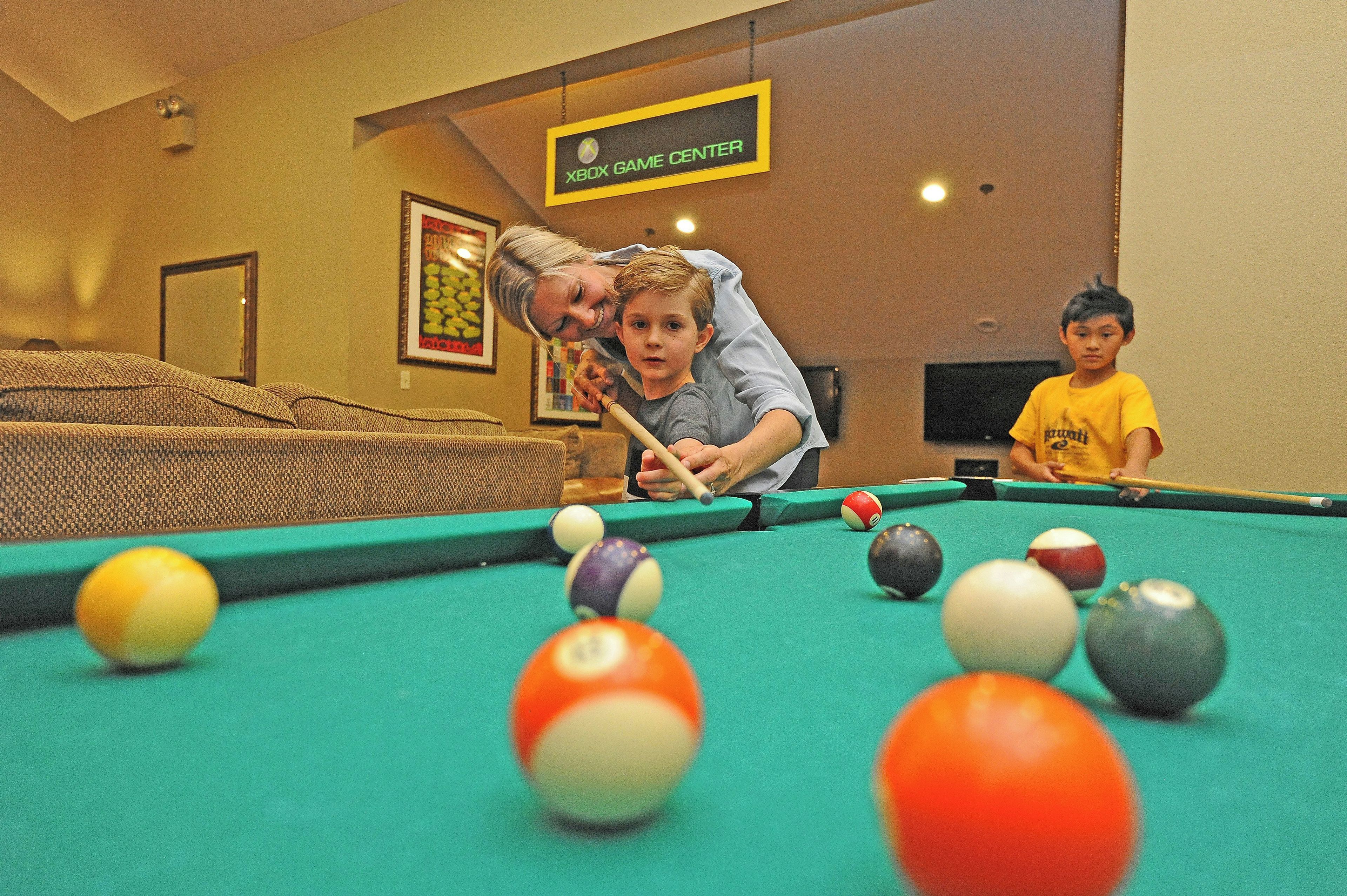 A pool table with balls, a sofa, and a sign indicating an Xbox game center.