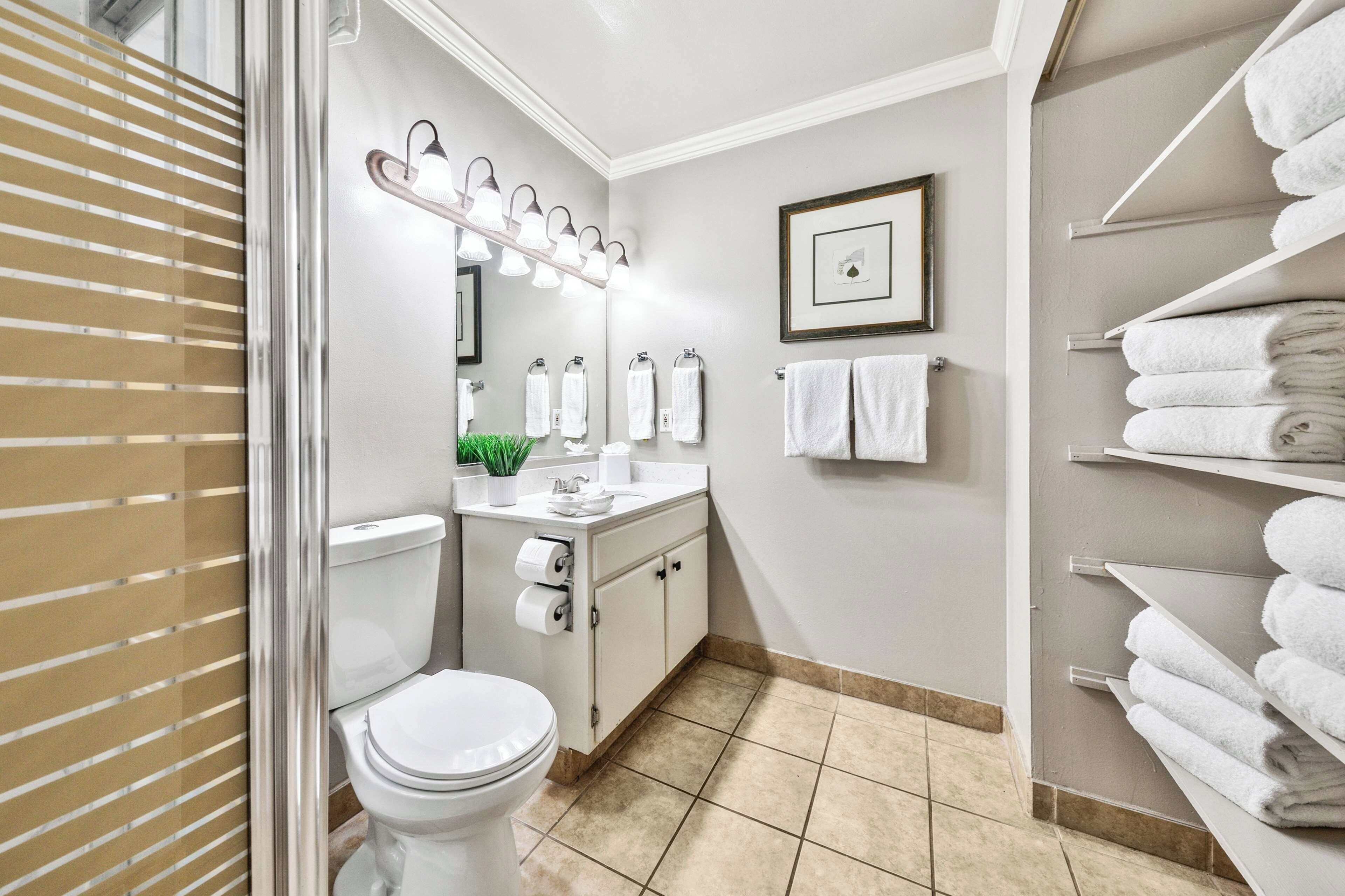 Een badkamer met toilet, wastafel, spiegel en handdoekhouder.