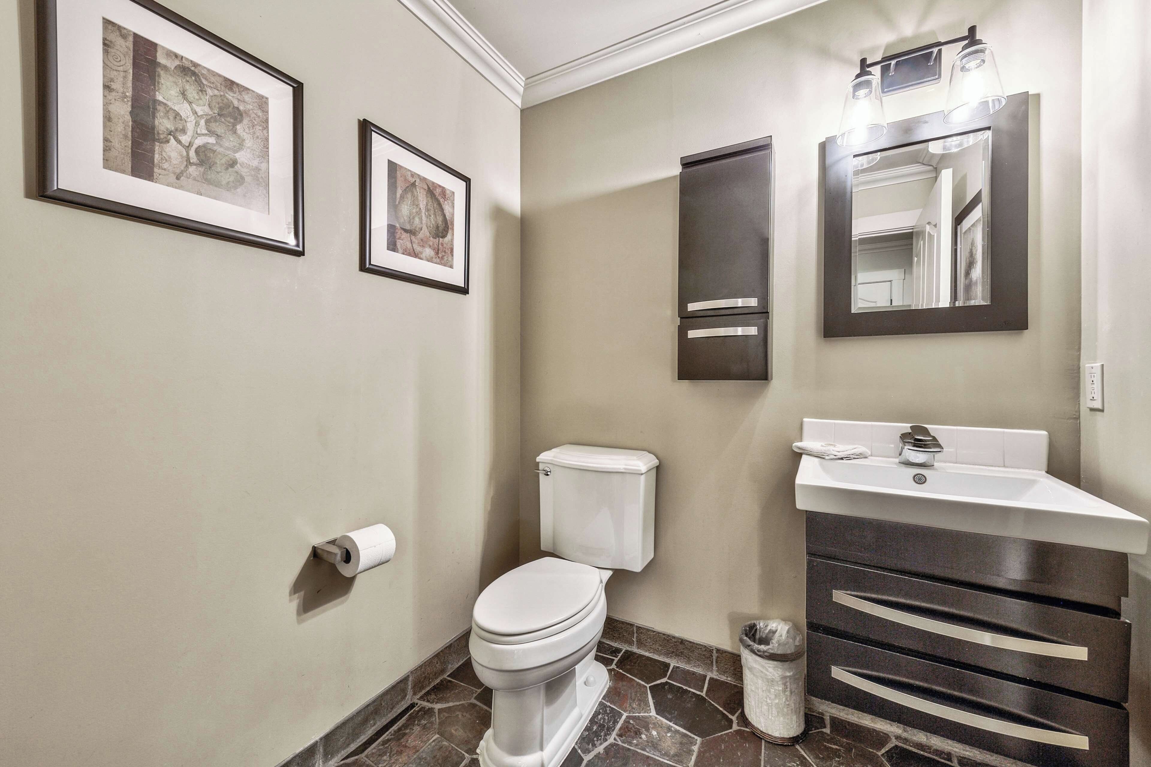 Ein Badezimmer mit Toilette, Waschbecken und zwei gerahmten Bildern an der Wand.