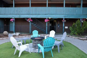 A patio area with outdoor seating, a stone fire pit, and a staircase leading to a building with a sign reading 'Lobby.'