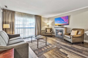Una sala de estar con sofá, sillón, mesa de centro, chimenea y un cuadro en la pared.
