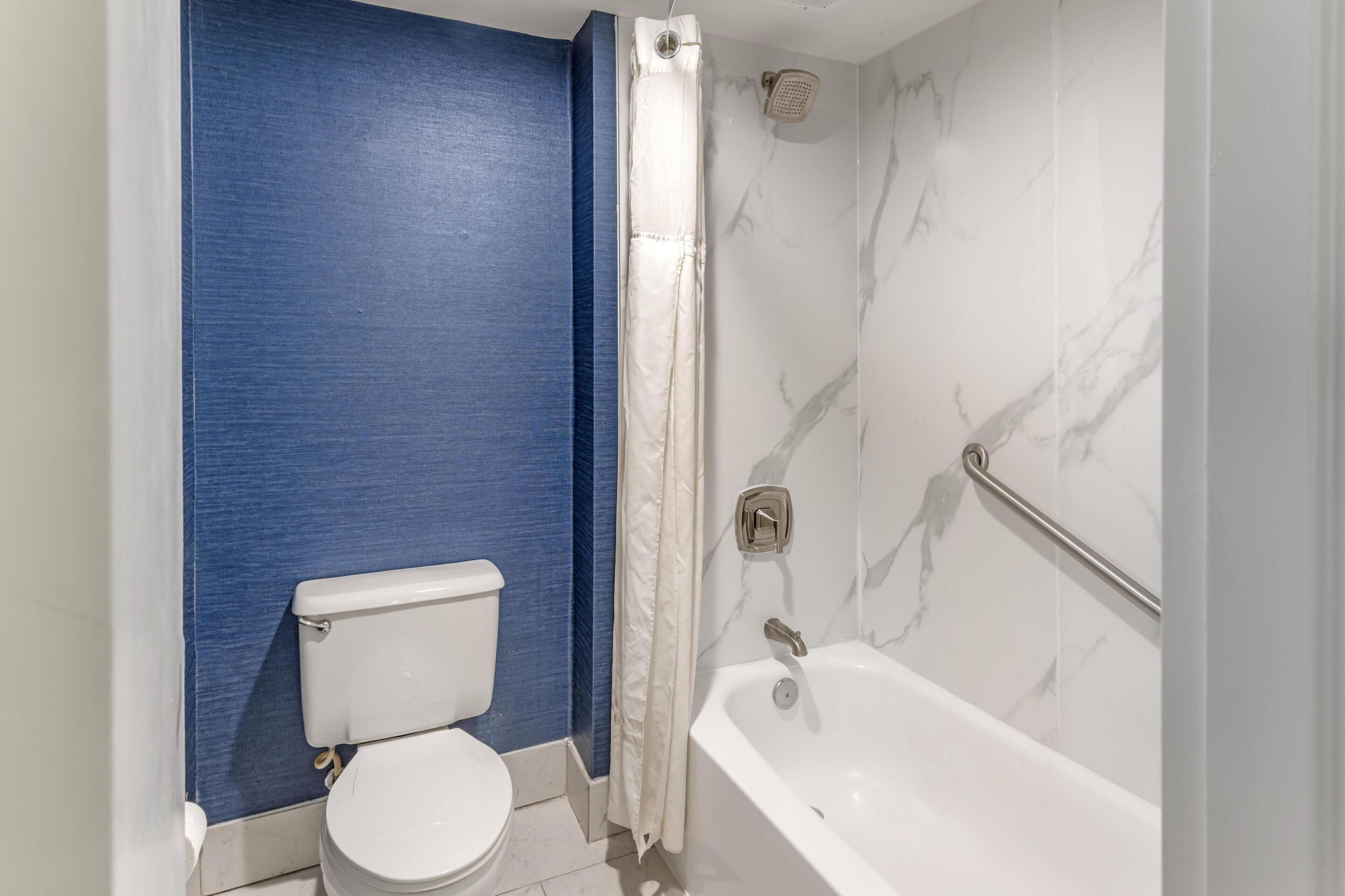 Une salle de bain équipée de toilettes, d’une baignoire et d’un rideau de douche.