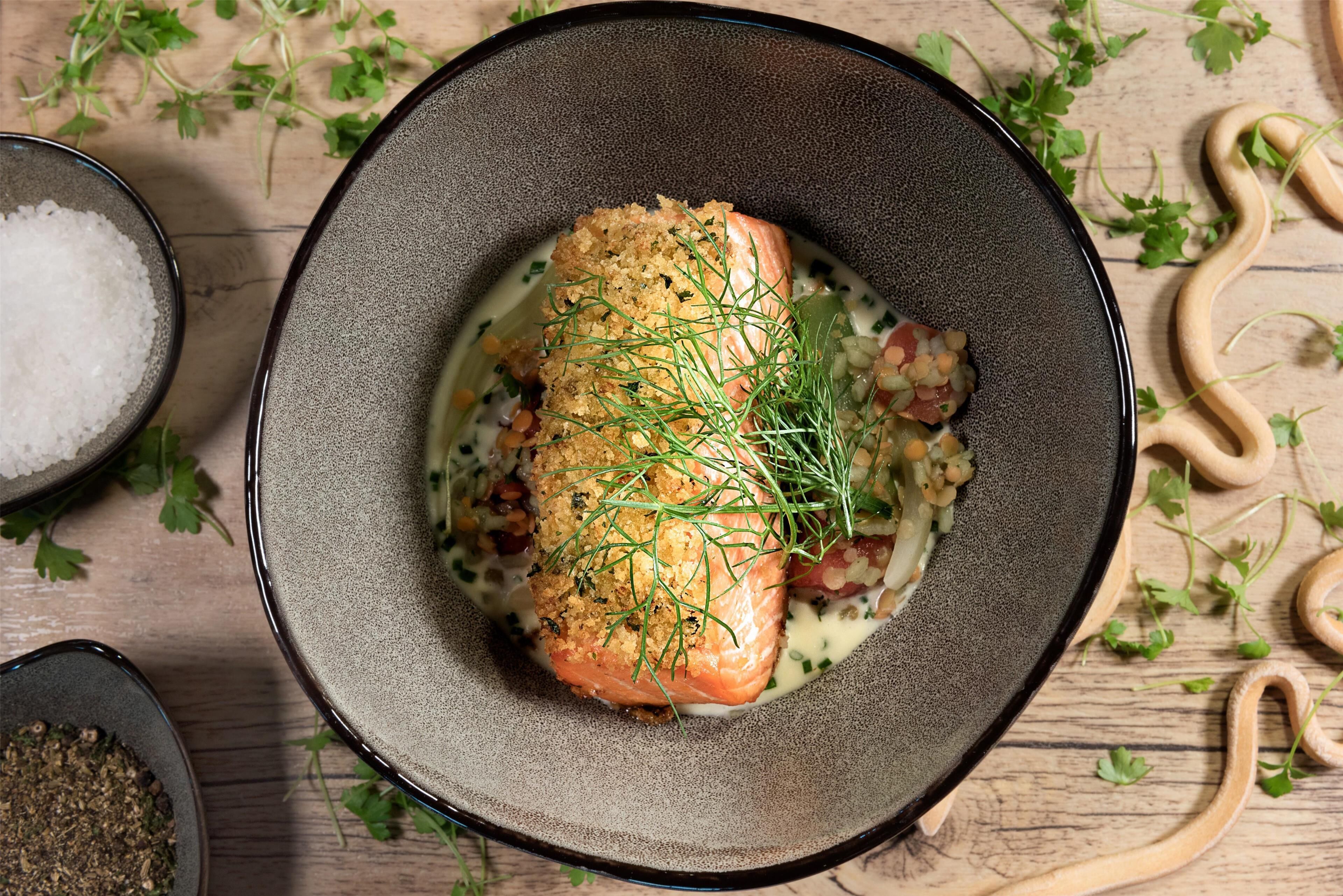 A dish with salmon and herbs on a plate.