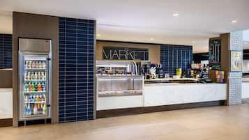 Un quiosco moderno con mostrador refrigerado y estación de café, identificado como 'THE MARKET'.