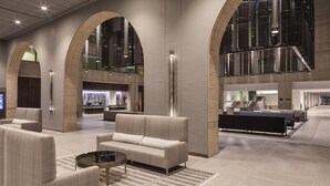 A spacious lobby with a modern design, featuring a reception desk, seating area with sofas and chairs, and large windows providing natural light. - Hyatt Regency Schaumburg Chicago (Schaumburg)