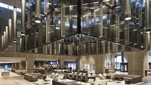 A spacious lobby with modern seating, a bar area, and a high ceiling with reflective panels. - Hyatt Regency Schaumburg Chicago (Schaumburg)