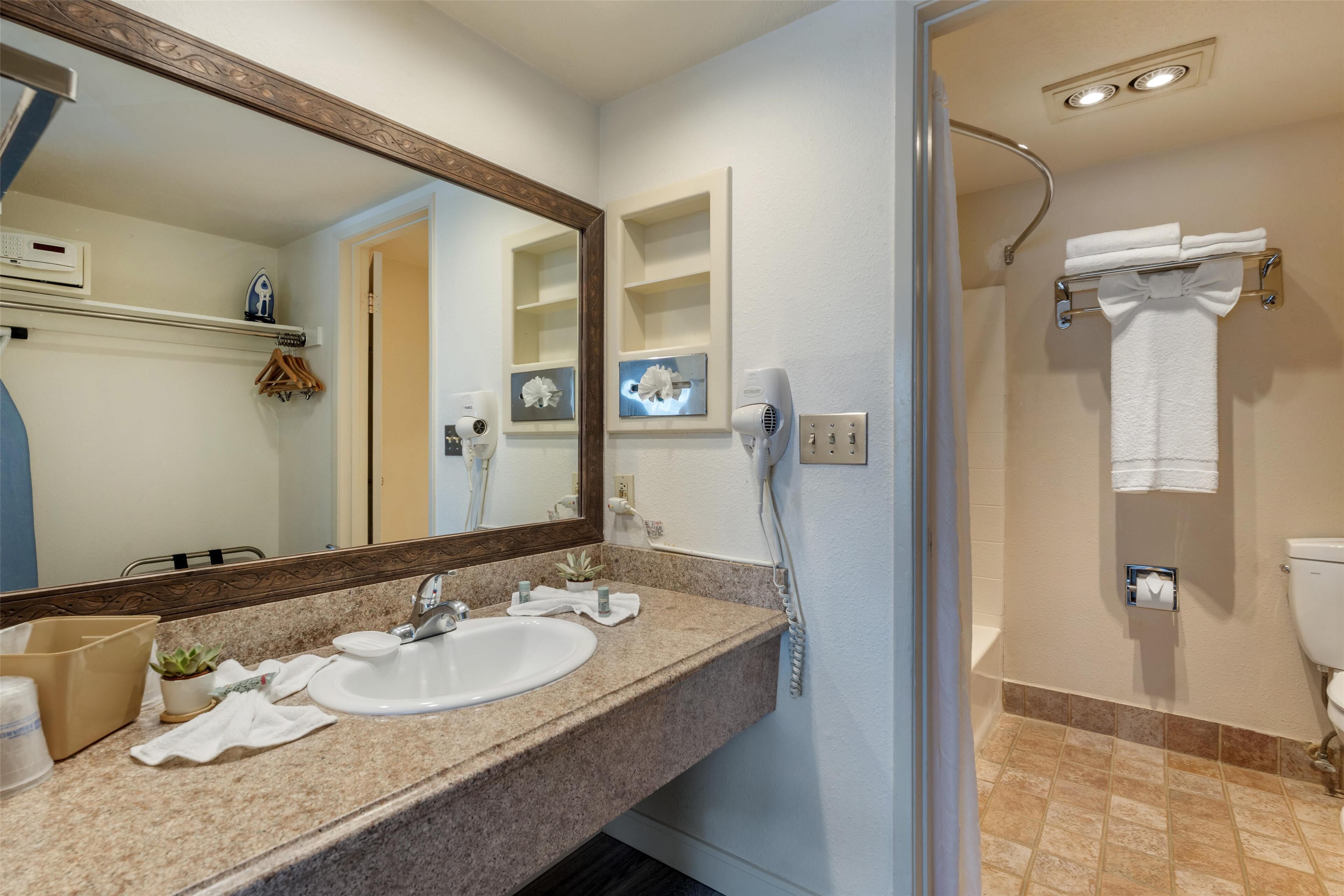 Une salle de bain équipée d’un lavabo, d’un miroir, d’un porte-serviettes et d’une zone douche.