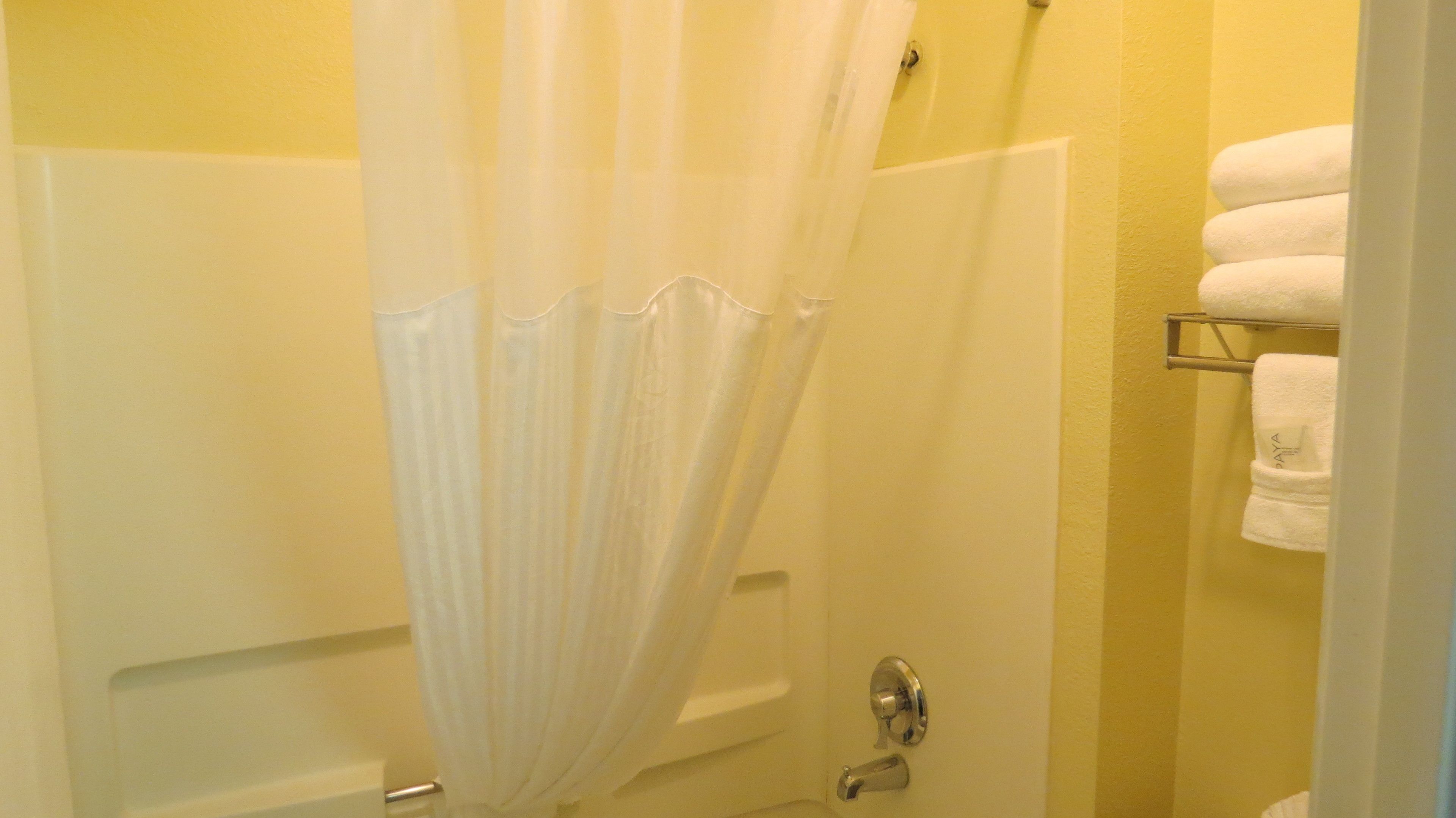 Un baño con cortina de ducha, bañera y un perchero con toallas.