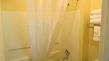 Un baño con cortina de ducha, bañera y un perchero con toallas.