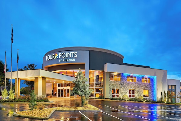 A modern hotel with a curved facade, large glass windows, and a well-lit entrance.
