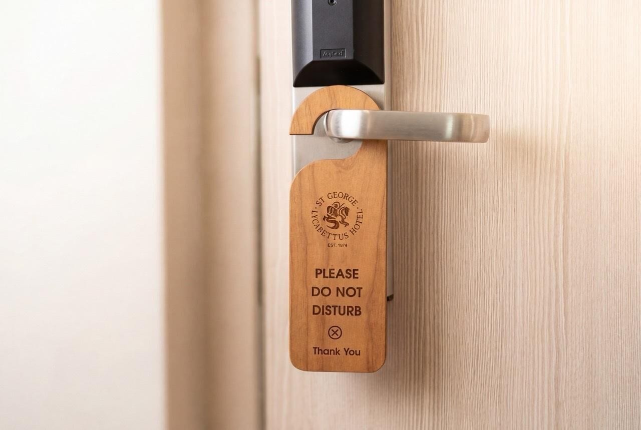 A hotel door with a wooden sign that reads 'PLEASE DO NOT DISTURB Thank You' and the hotel's name and establishment year.