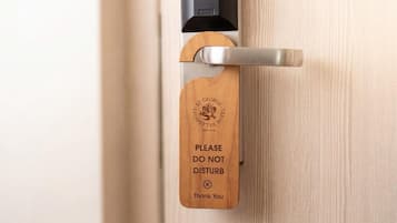 A hotel door with a wooden sign that reads 'PLEASE DO NOT DISTURB Thank You' and the hotel's name and establishment year.