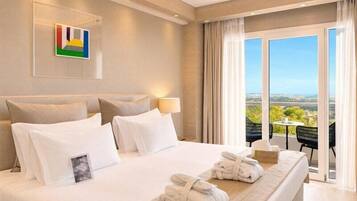 A hotel room with a large bed, a view of the outdoors, and a balcony with chairs.