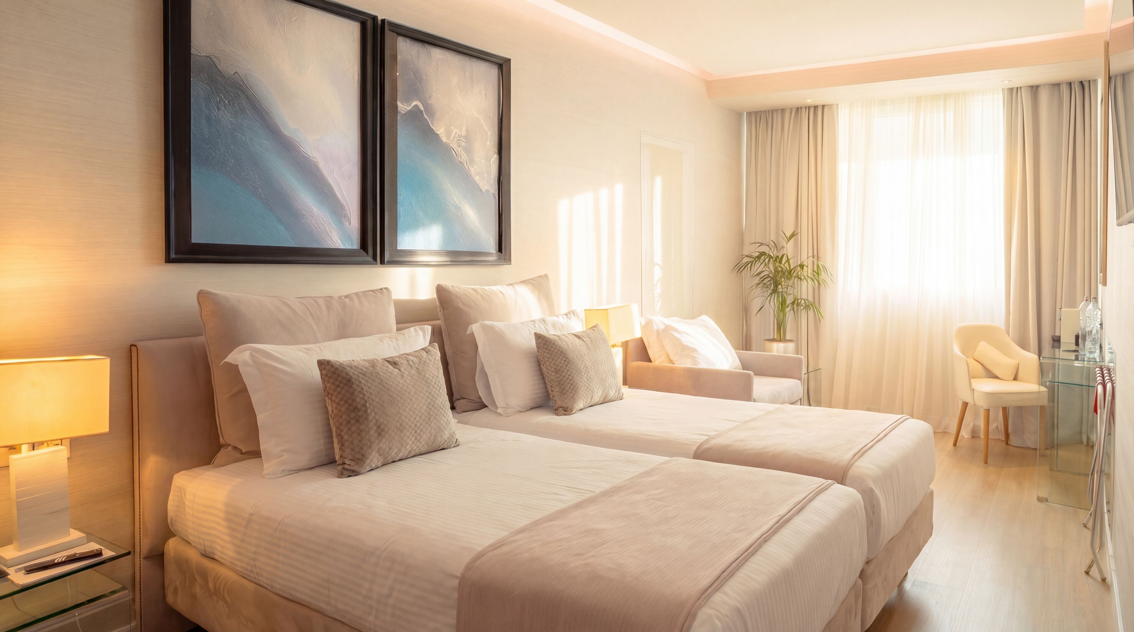 A hotel room with two beds, a desk, a chair, a lamp, and a plant.