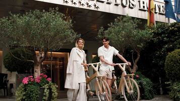 A hotel entrance with a sign reading "CABERTUS HOTEL." There are two people standing beside bicycles.