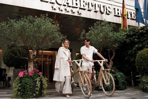 Hotellin sisäänkäynti, jossa on kyltti, jossa lukee: ”CABERTUS HOTEL”. Kaksi ihmistä seisoo pyörien vieressä.