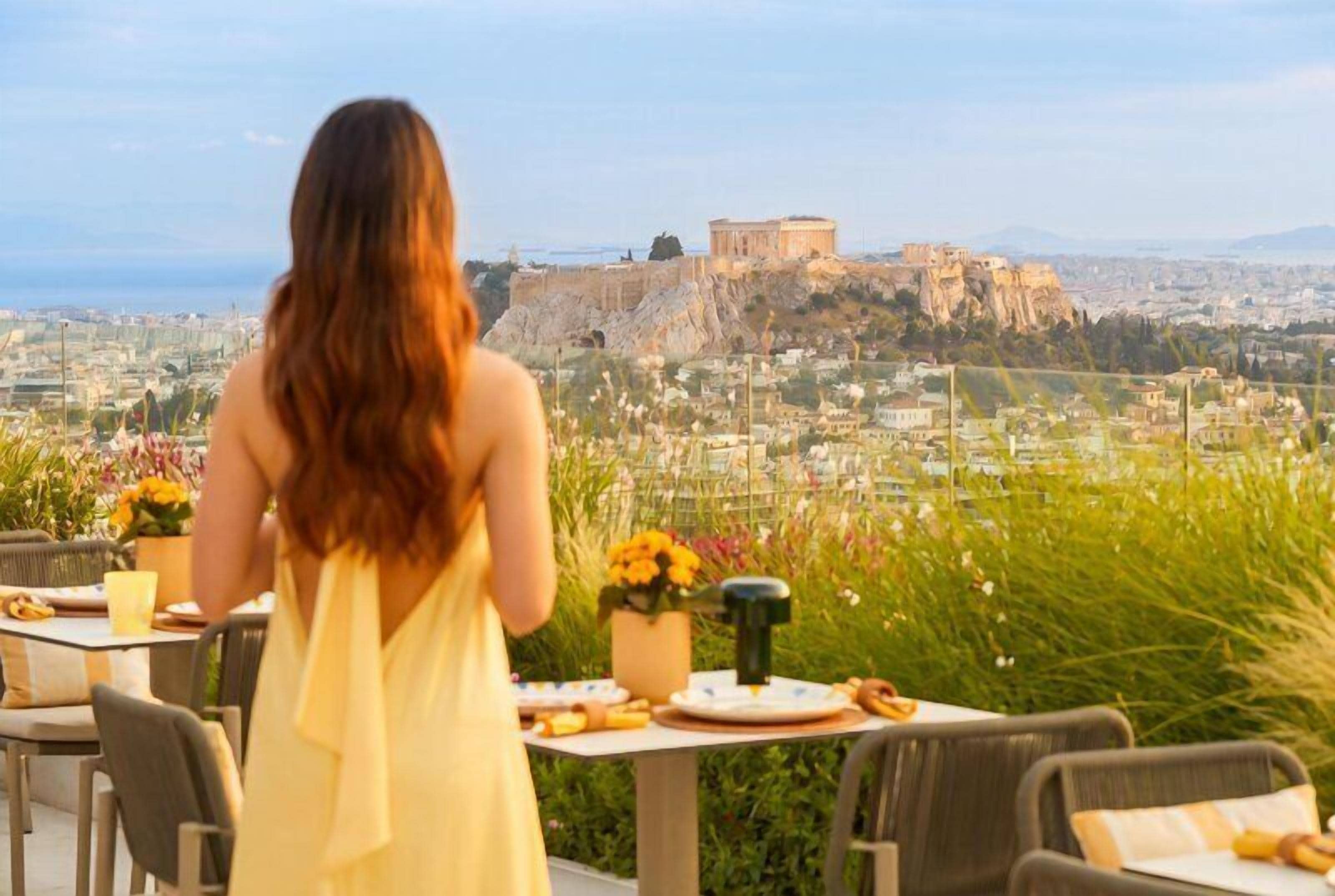 Una persona cenando en una mesa al aire libre con vistas a un edificio histórico y al paisaje urbano.