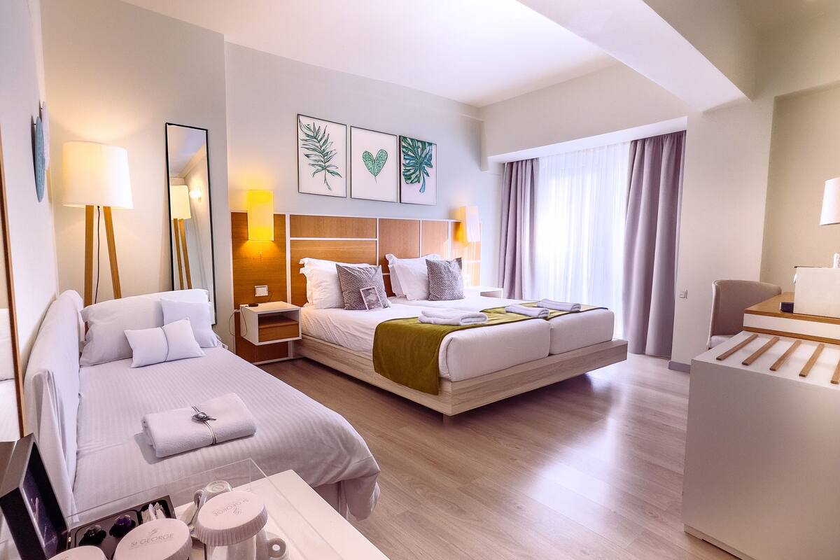 A modern hotel room with two beds, a desk, and a vanity with toiletries.