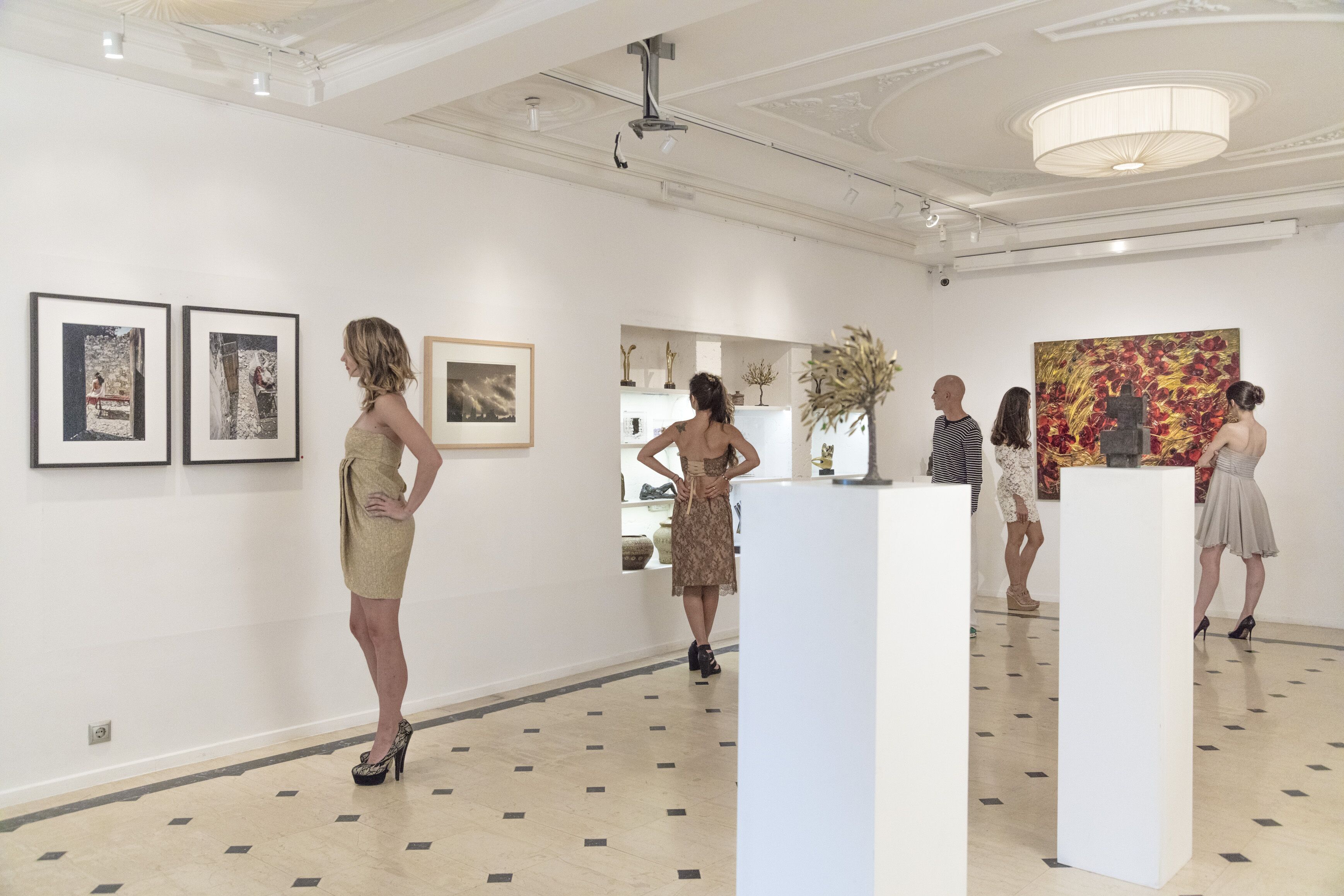 Une galerie d’art aux murs blancs et aux sols carrelés, où sont exposées diverses œuvres d’art et sculptures.