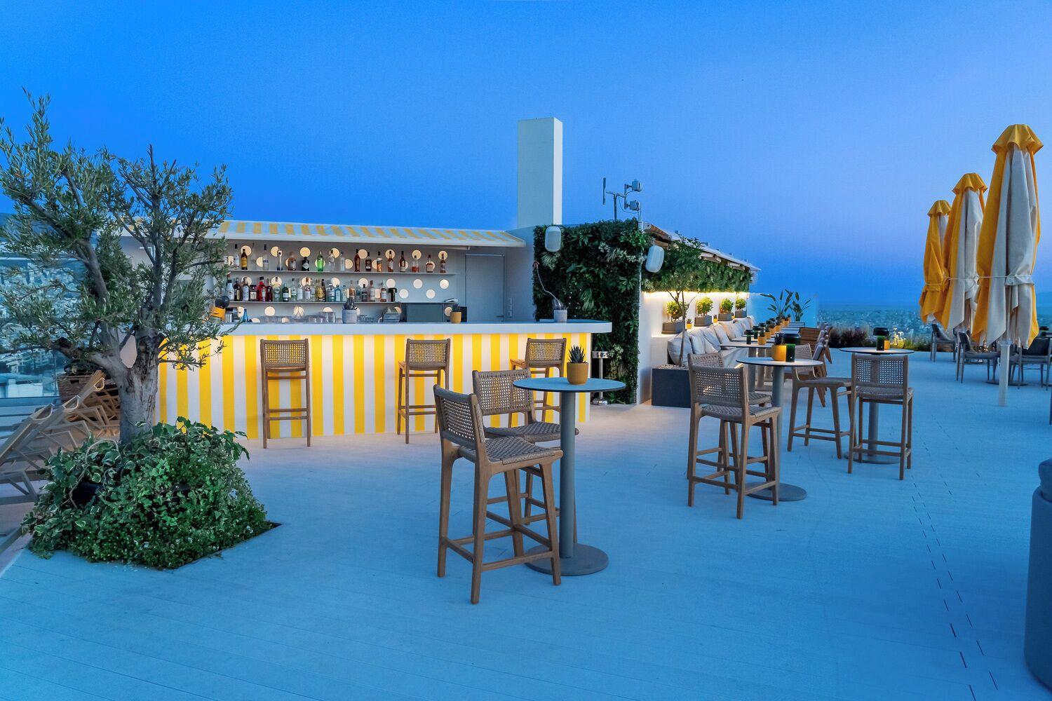 A rooftop bar with a bar counter, seating area, and outdoor umbrellas.