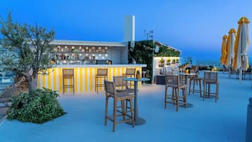 A rooftop bar with a bar counter, seating area, and outdoor umbrellas.