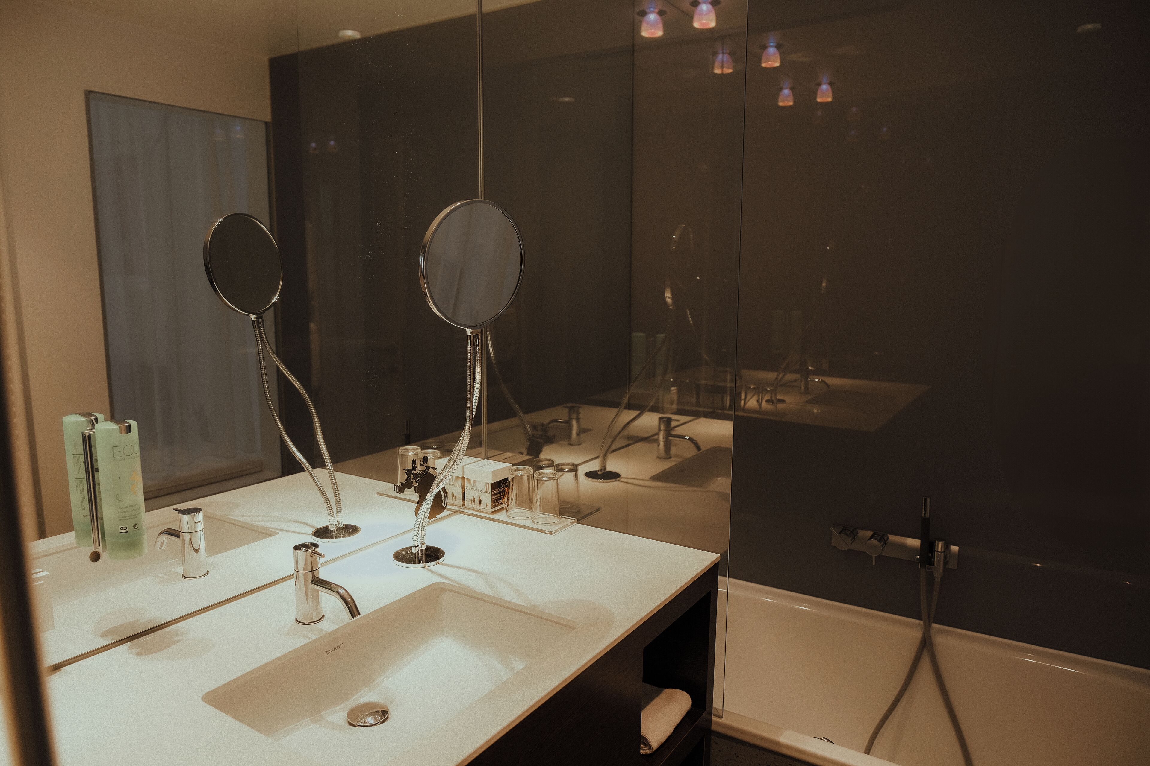 Ein modernes Badezimmer mit einem großen Spiegel, zwei Waschbecken und einer Badewanne.