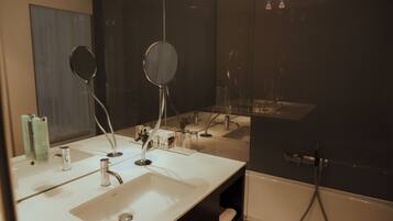 Ein modernes Badezimmer mit einem großen Spiegel, zwei Waschbecken und einer Badewanne.