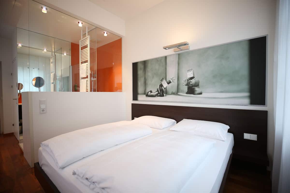 A hotel room with a large bed, a mirror, and a painting on the wall.