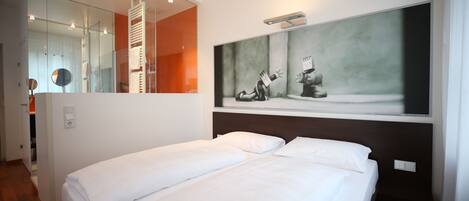 A hotel room with a large bed, a mirror, and a painting on the wall.