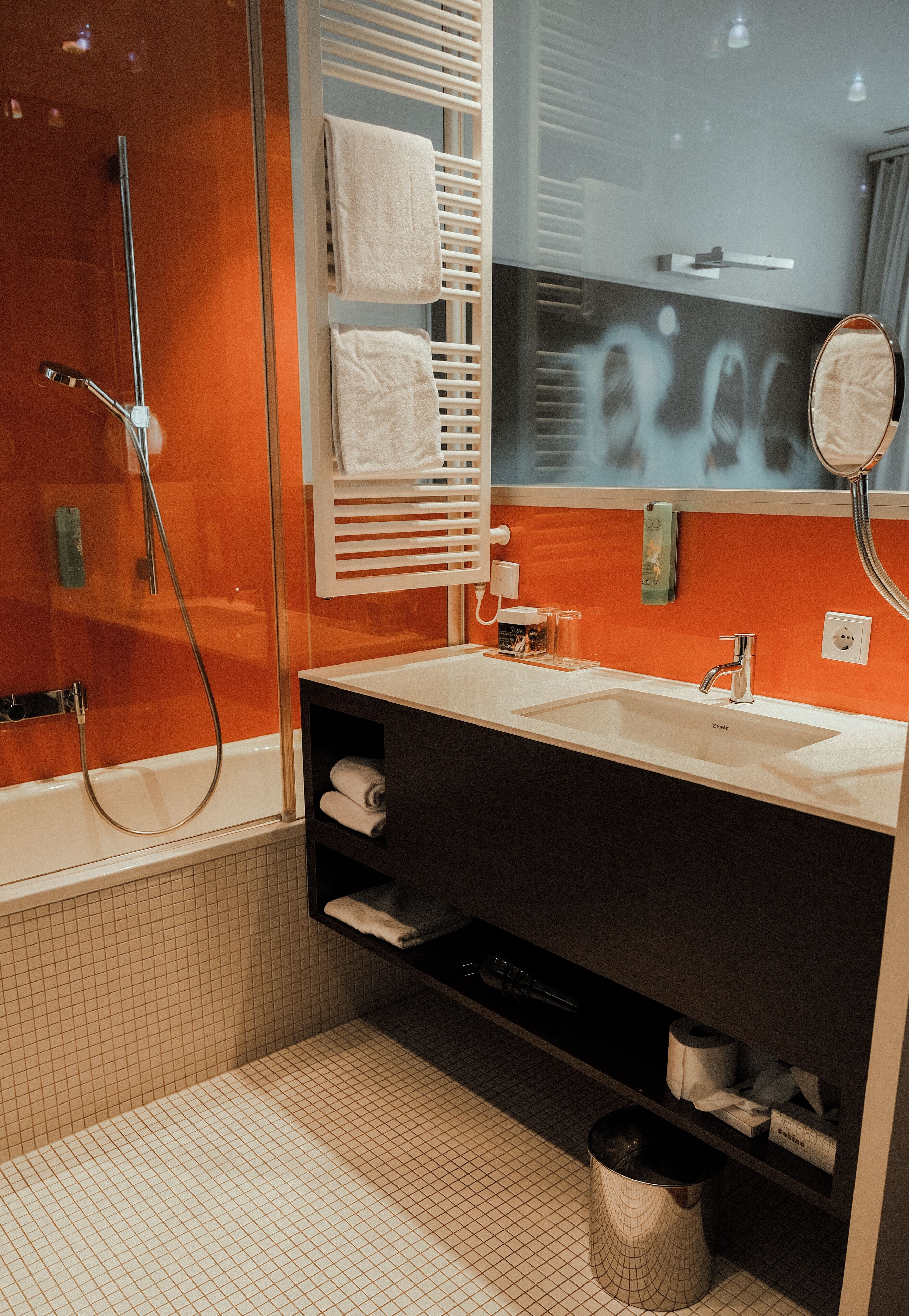 A modern bathroom with a glass-enclosed shower, a white sink, and a dark vanity.