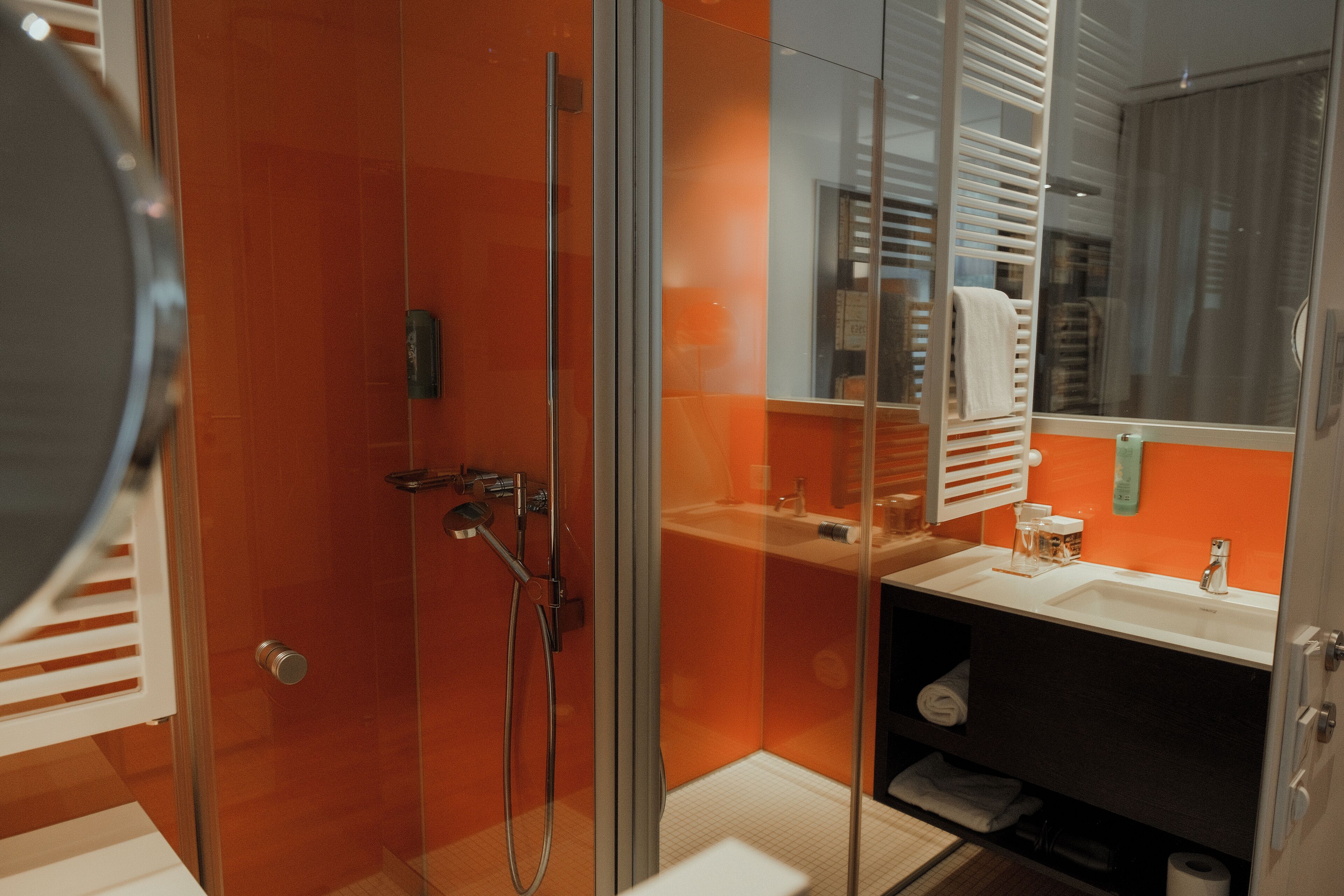 A modern bathroom with a glass-enclosed shower, a white sink, and a mirror.