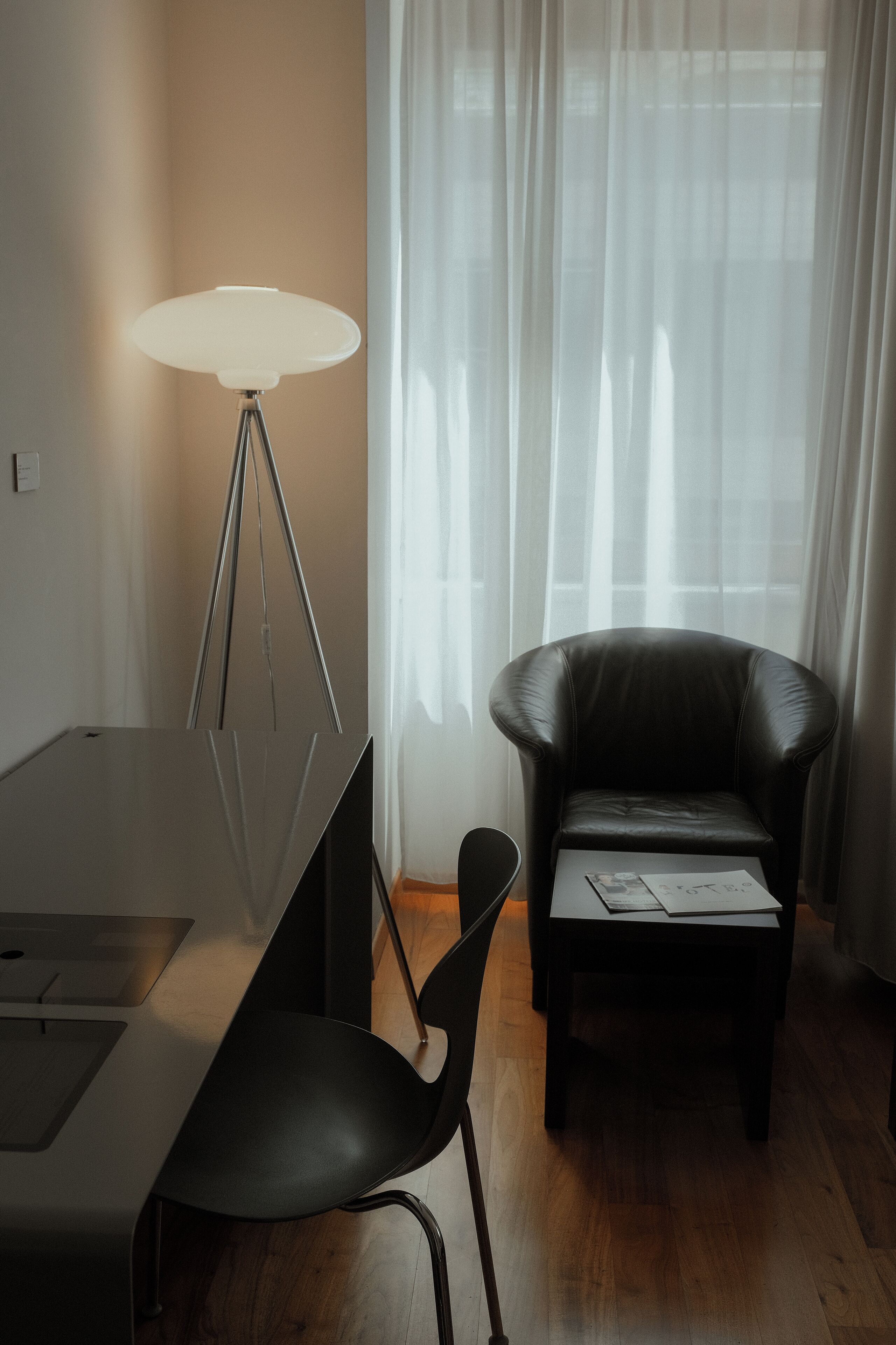 Une chambre moderne équipée d’un bureau, d’une chaise, d’une lampe et d’un fauteuil en cuir.