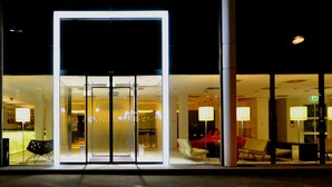A modern hotel entrance with glass doors, indoor seating, and ambient lighting. - arte Hotel Linz (Linz)