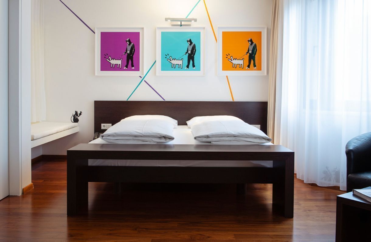 Una cama bien hecha con sábanas blancas en una habitación de hotel moderna.