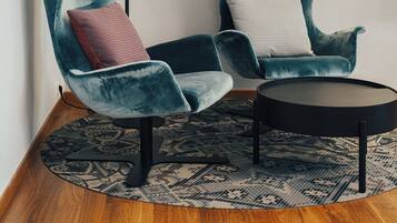 Two teal armchairs with patterned cushions, a small round table, and a black floor lamp.