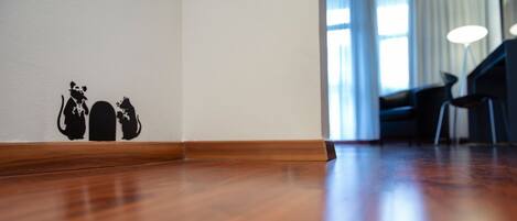 A wooden floor leading to a doorway with a wall decal of two cats.