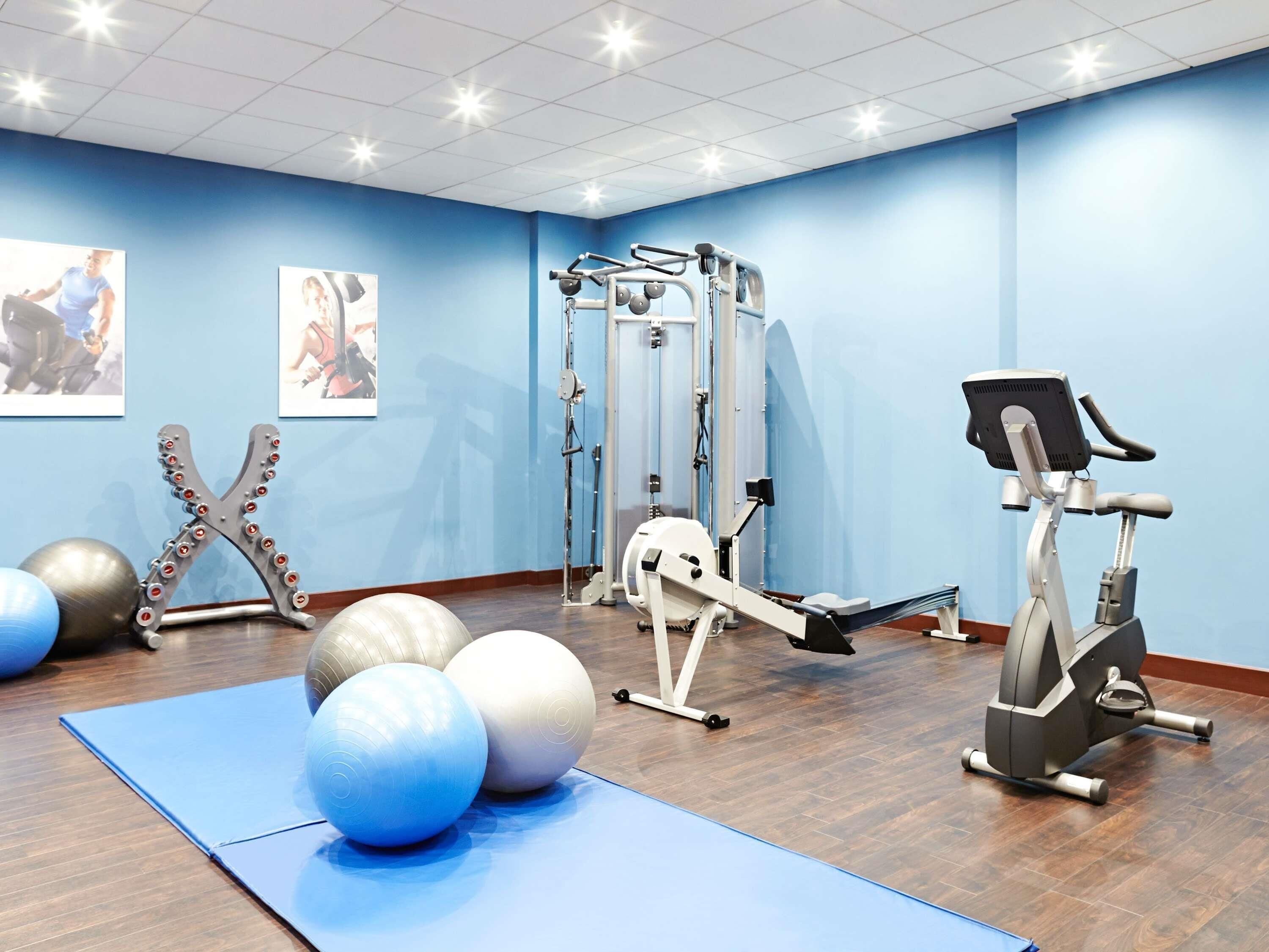 A gym with exercise equipment, exercise balls, and a blue mat.